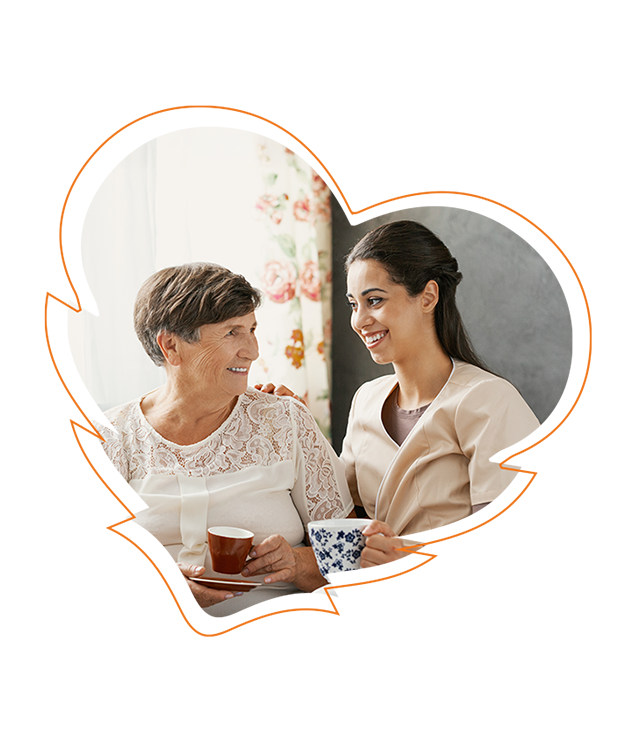 An elderly woman and a younger woman sharing a warm moment while holding cups of tea, with a heart-shaped graphic overlaid on the photo.
